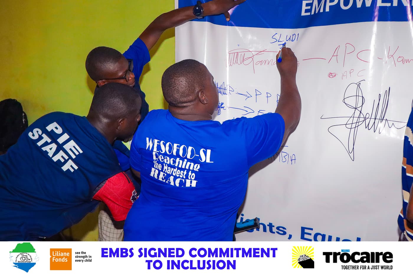 WESOFOD-SL and PIE staff sign a large commitment-to-inclusion poster alongside representatives of electoral bodies and political parties