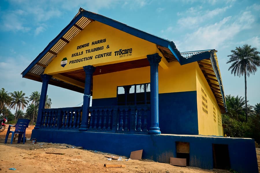 The blue and yellow Denise Harris Skills Training and Production Centre in Pujehun under a clear sky